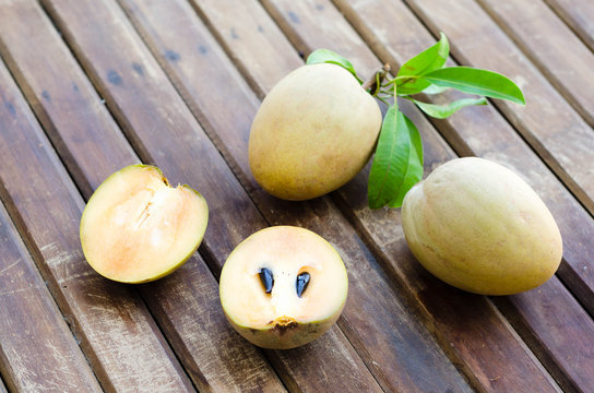 Fresh sweet sapodilla fruit with leaves on wooden background