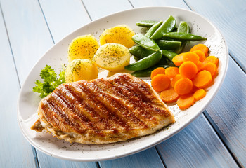 Roast chicken fillet and vegetables on white background 