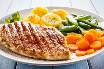 Roast chicken fillet and vegetables on white background 