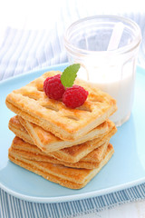 cookies decorated with raspberries and a glass of milk for breakfast