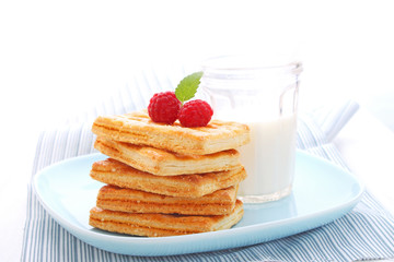 cookies decorated with raspberries and a glass of milk for breakfast
