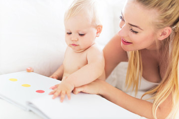 Obraz na płótnie Canvas Mother reading book with baby