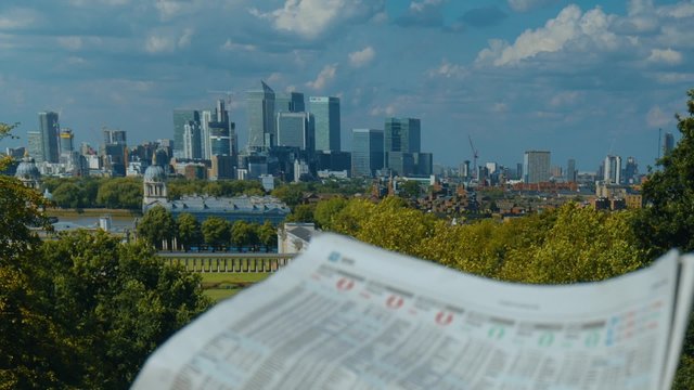 Investor reading a newspaper with London's financial district in the backdrop