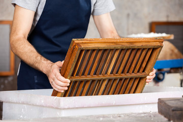 Midsection Of Worker Dipping Mold In Pulp And Water
