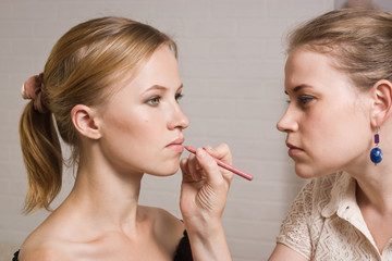 Beautiful woman having lipstick applied by make-up artist