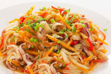 Rice noodles with vegetables and seafood on  white plate.