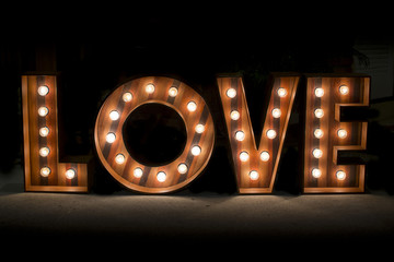 Fototapeta na wymiar Wording Love sign with light bulb isolate on black background