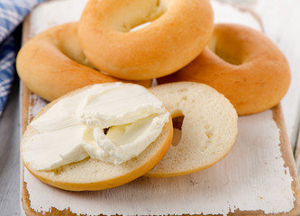 Bagels with cream cheese on  wooden board.