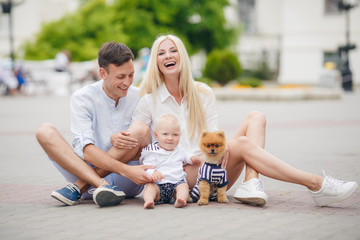 Mother, father, little boy and dog having fun in the green park.