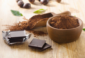 Chocolate bars and a wooden bowl of cacao powder.