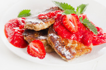 Pancakes with strawberry jam and mint leaves.