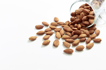 Almonds in the glass and pour on white background, selective focus point