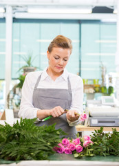 Florist Cutting Stem On Rose At Counter In Flower Shop