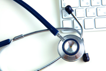 A medical stethoscope near a laptop on a wooden table, on white