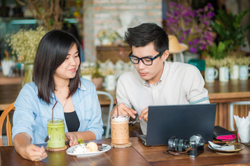 Couple business talking with laptop computer and drinking in caf