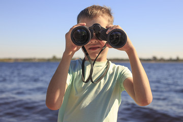 watching through binoculars. Boy looks through binoculars at the river, the position of a full-face