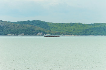 Obraz premium A cargo ship on the sea, mountain background