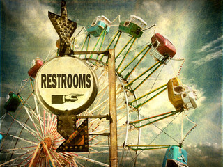 aged and worn vintage photo of ferris wheel and rest room sign