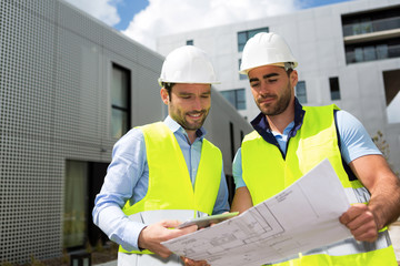 Engineer and worker checking plan on construction site