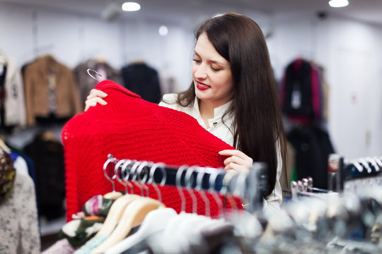 Ordinary woman choosing sweater at store