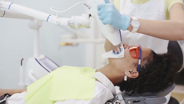 Oral hygiene, dental care: Dentist with a patient in a dental clinic teeth whitening procedure. Teeth whitening beam machine session
