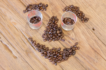 Coffee beans in smile face shape on wood table