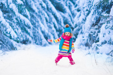 Fototapeta na wymiar Little girl playing in snowy winter forest