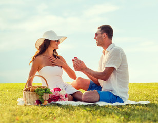 smiling couple with small red gift box on picnic