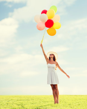 smiling young woman in sunglasses with balloons