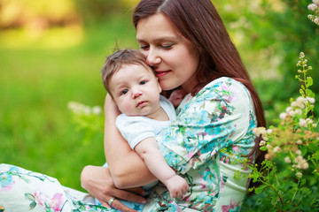 Mother kisses baby son, close-up, summer