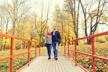 smiling couple hugging on bridge in autumn park