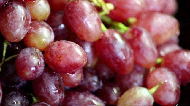 Red grapes revolves on black glossy background