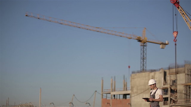 Engineer builder using tablet at a construction site. Long shot