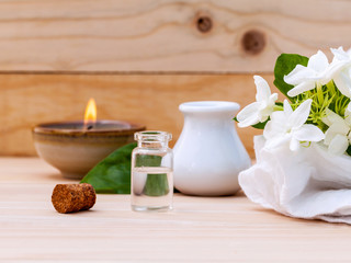 Aroma oil bottles arranged with jasmine flowers on wooden backgr