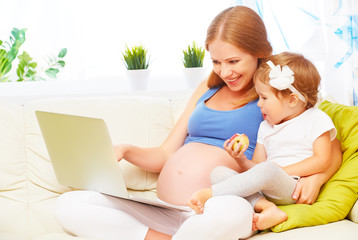 Happy family pregnant woman and child with a laptop at home