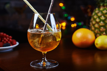 Bright strong alcoholic cocktail with a creative decoration of chocolate sticks and ice cubes on a table in a restaurant with backgrounds of colored disco lights. soft focus and beautiful bokeh.