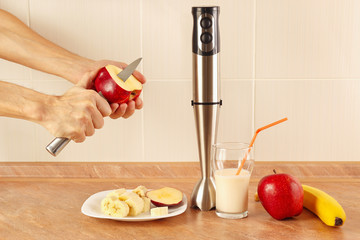 Hands cooks cut apple to prepare the smoothie on the table