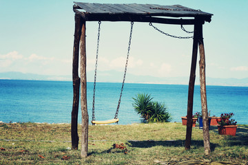 Wooden swing on the beach, sea view, nature background, vintage photo