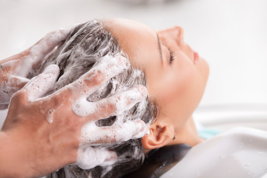 Cheerful young woman has her hair washed in beauty shop
