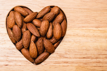 Heart shaped almonds on wooden surface background
