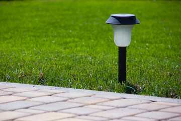 Solar Lantern is on the green lawn next to a paved garden path