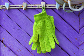 Green gloves against violet boards. A hanger on a wall of the private house. Abstract symbol of...