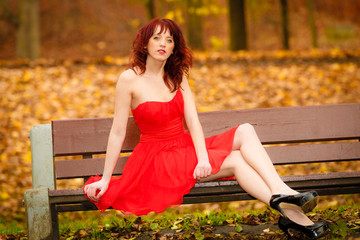 woman red dress sitting on bench in autumn park