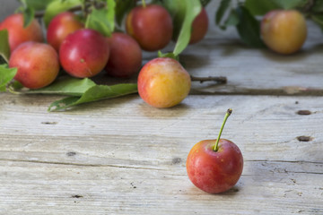 Wild red plums on an old wooden board