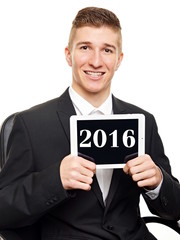 Happy new 2016 year. Young businessman in suit shows tablet pc with the numeral 2016.
