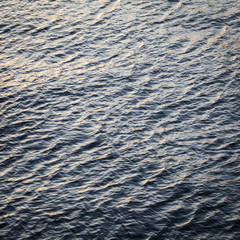Water surface with ripples and sunrays reflection