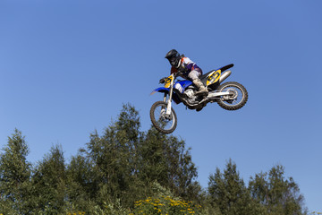 Obraz premium A man jumping on his motorcycle and some trees in the background