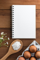 Notebook white on a wooden floor with egg dishes.