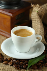 Cup of coffee with beans on table close up
