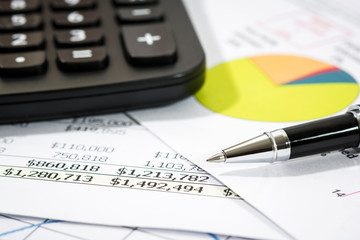 Black pen with financial report and calculator  